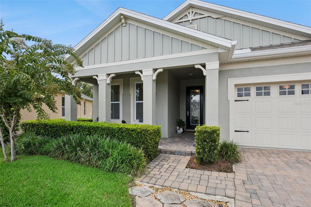 A light-colored house exterior features a covered front porch, brick walkway, and attached garage — 1048 WOOD DALE CIRCLE, OVIEDO, FL