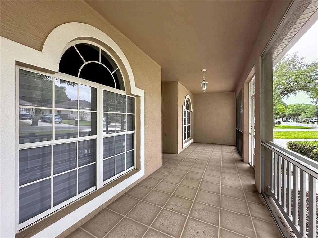 A covered patio with tiled flooring, white railings, and arched windows along the exterior wall — 4127 KINGSLEY STREET, CLERMONT, FL