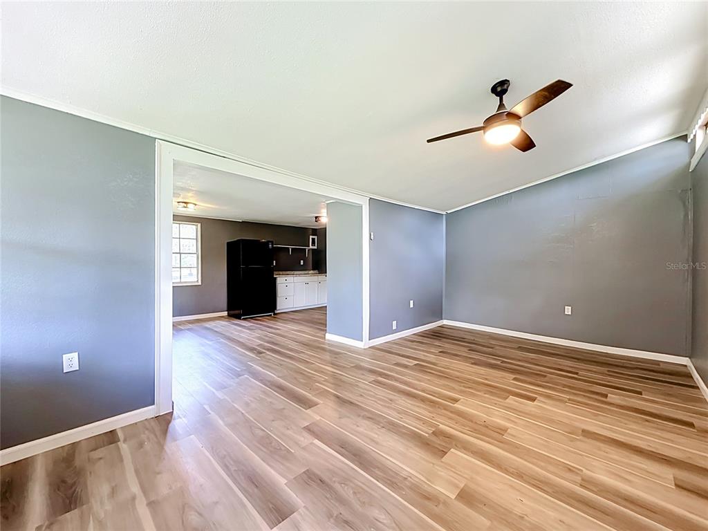 A living room with gray walls and wood-look flooring opens into a kitchen beyond — 1880 CR 422, LAKE PANASOFFKEE, FL