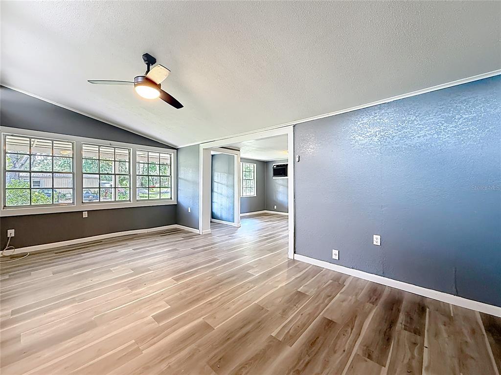 An interior room features gray walls, light wood-look flooring, a ceiling fan, and large windows — 1880 CR 422, LAKE PANASOFFKEE, FL