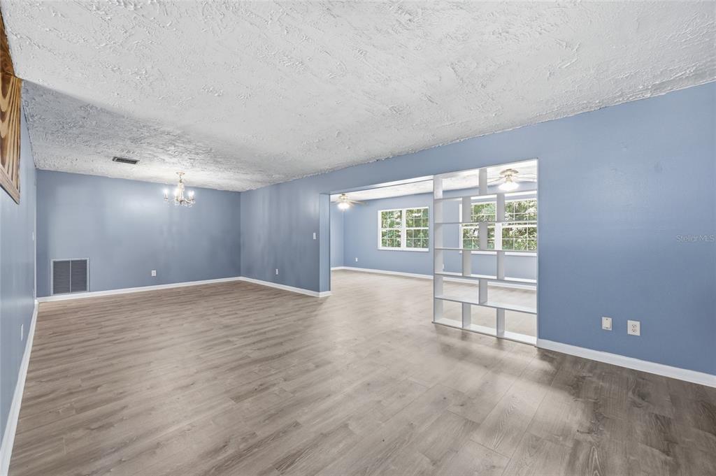 A spacious living area with blue walls, wood-look flooring, and a white room divider — 9350 NW 114TH STREET, CHIEFLAND, FL