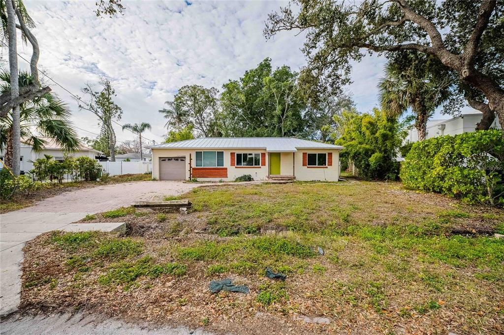 A single-story house with a metal roof, brick accents, and a large front yard — 6213 SANDERS DRIVE, TAMPA, FL
