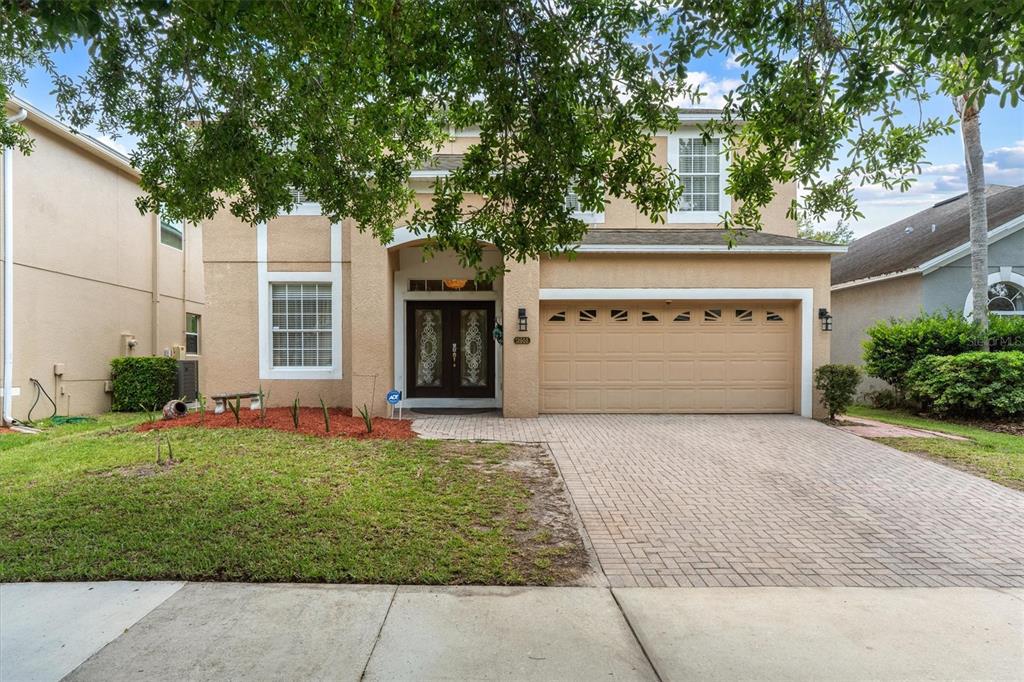 A two-story tan stucco house with a paved driveway and a double-car garage — 12955 MOSS PARK RIDGE DRIVE, ORLANDO, FL