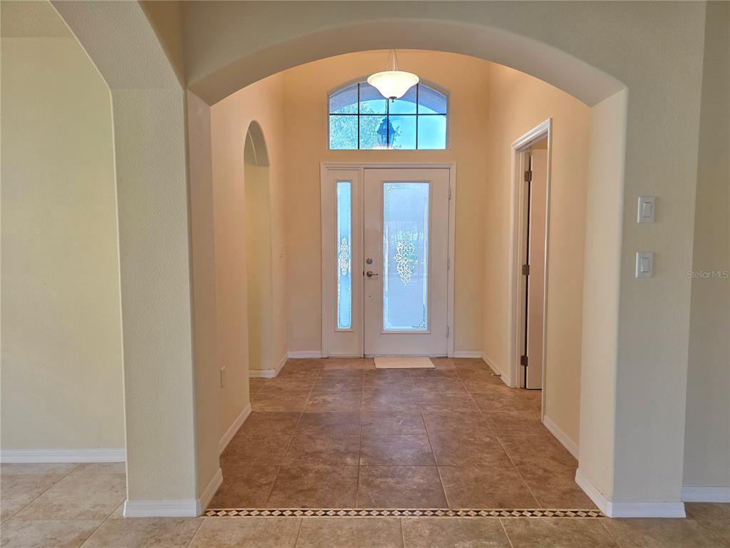 An entryway features tile flooring, an arched opening, and a glass-paneled front door with transom — 4284 HIGH RIDGE AVENUE, SPRING HILL, FL