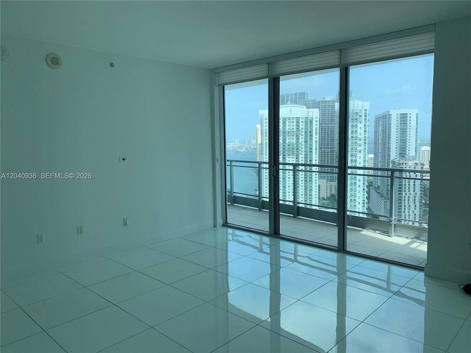 An empty room with white tile floors and floor-to-ceiling windows overlooking a city skyline — 90 SW 3rd St # 3610, Miami FL 33130, MIAMI, FL