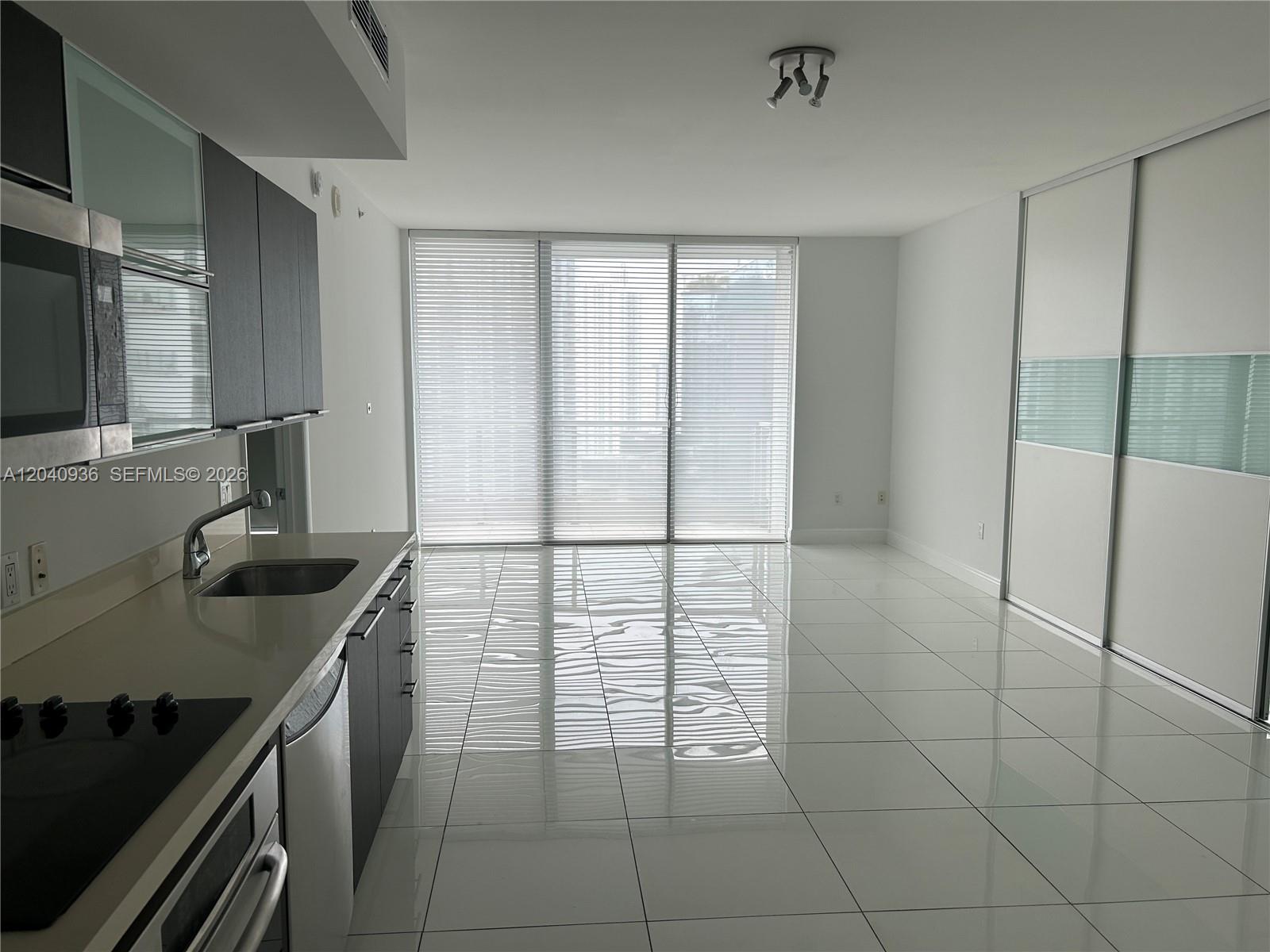 A modern kitchen and living area feature white tile floors and floor-to-ceiling window blinds — 90 SW 3rd St # 3610, Miami FL 33130, MIAMI, FL
