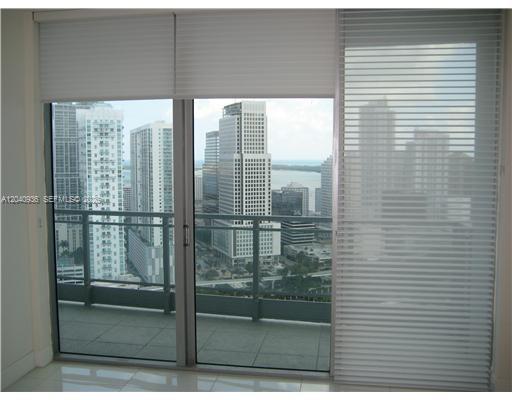 A view of a city skyline and water through a glass balcony door with blinds — 90 SW 3rd St # 3610, Miami FL 33130, MIAMI, FL