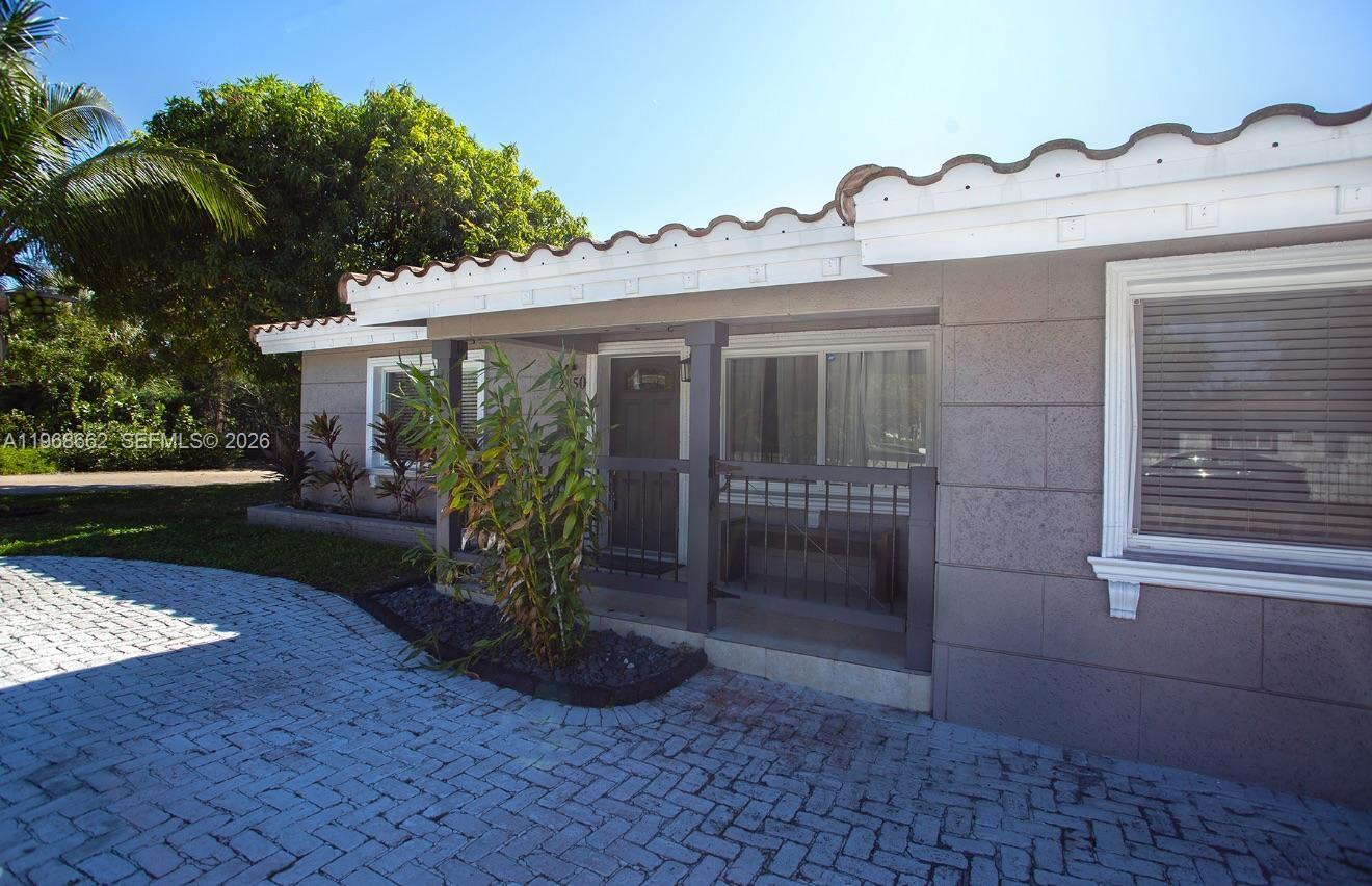 A single-story house exterior features a paved driveway, a covered entrance, and a tiled roof — 2450 NE 18th St, Pompano Beach FL 33062, POMPANO BEACH, FL