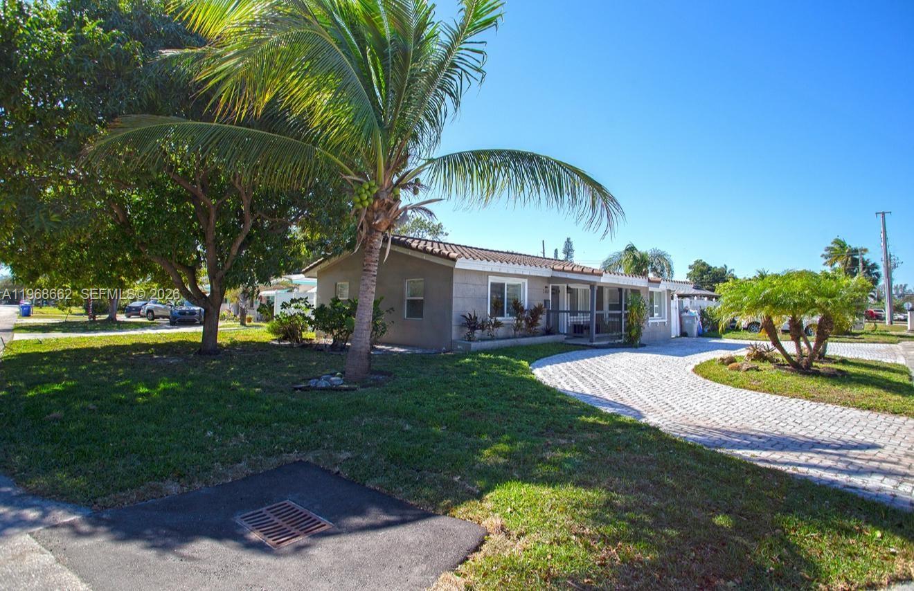A single-story house with a paved driveway and palm trees under a clear blue sky — 2450 NE 18th St, Pompano Beach FL 33062, POMPANO BEACH, FL