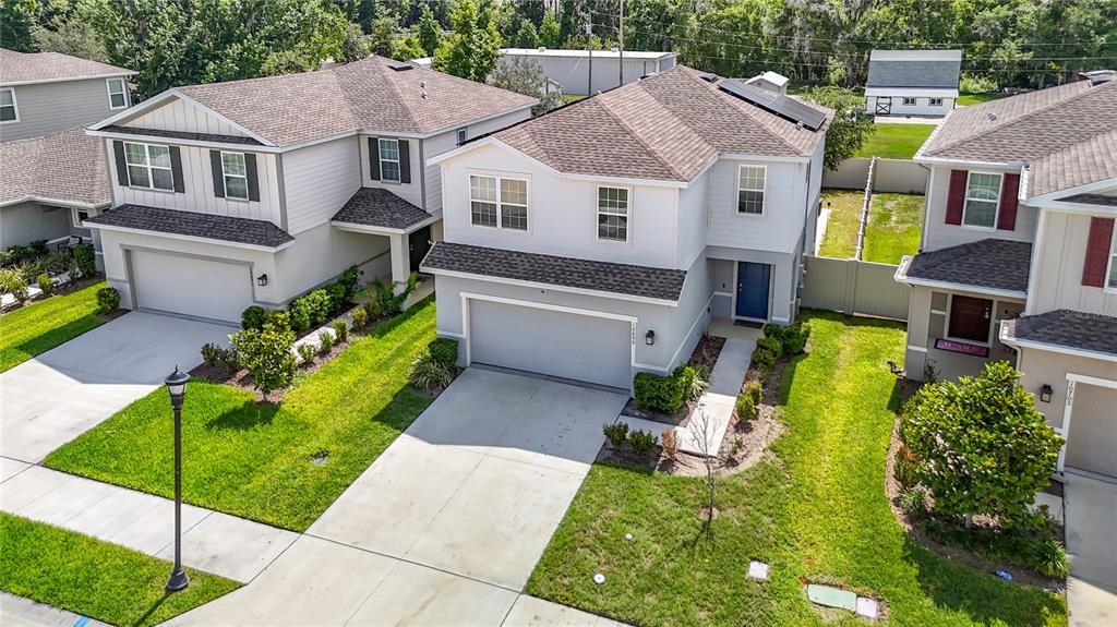 An aerial view shows three suburban two-story houses with driveways and green lawns — 10699 OLD SYCAMORE LOOP, LAND O LAKES, FL
