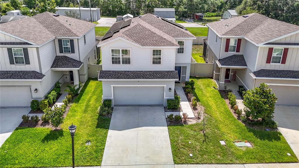 An aerial view shows three suburban houses with driveways, lawns, and shingled roofs — 10699 OLD SYCAMORE LOOP, LAND O LAKES, FL