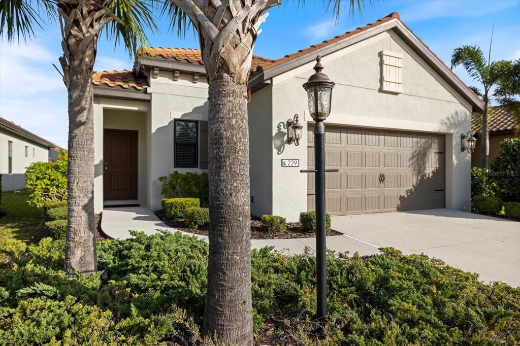 A single-story house with a beige stucco exterior, a two-car garage, and a palm tree — 229 LIVORNO WAY, NOKOMIS, FL