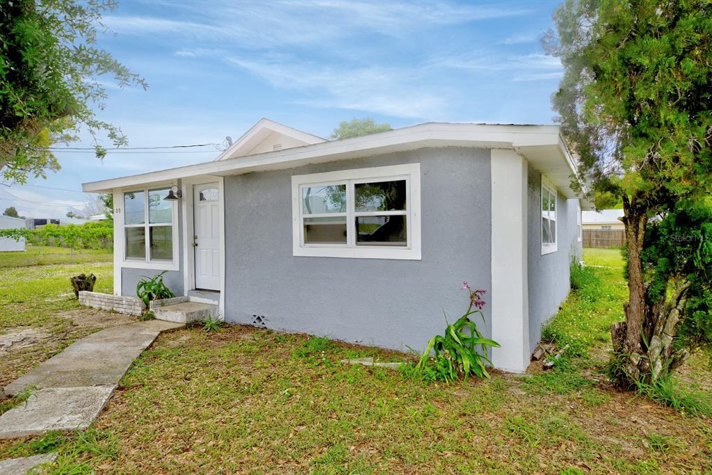 A single-story gray house with a white door and windows sits on a grassy lot — 109 S ANOKA AVENUE, AVON PARK, FL