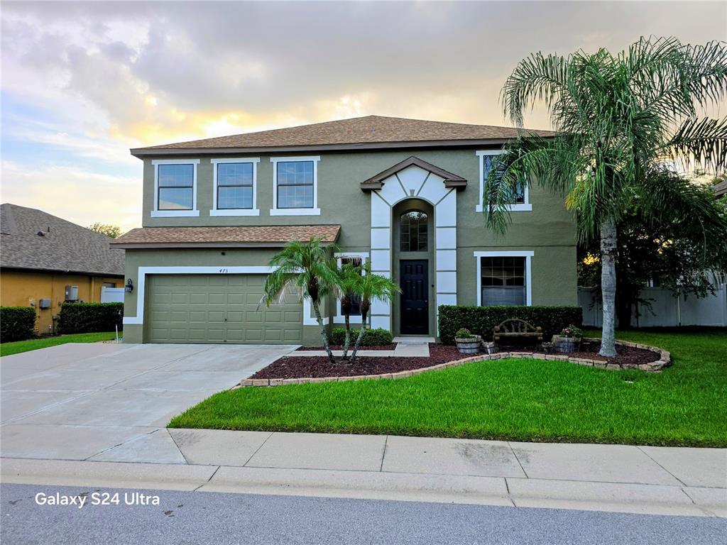 A two-story house with a green stucco exterior, a two-car garage, and a palm tree — 473 OAK LANDING BOULEVARD, MULBERRY, FL