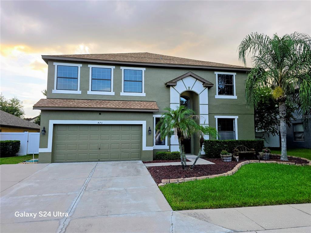 A two-story olive green house with a two-car garage and a palm tree in front — 473 OAK LANDING BOULEVARD, MULBERRY, FL