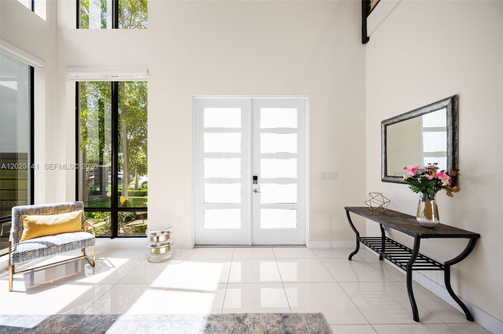 A bright entryway features white tile floors, a double front door, and a console table — 8763 NW 157th Ter, Miami Lakes FL 33018, MIAMI LAKES, FL