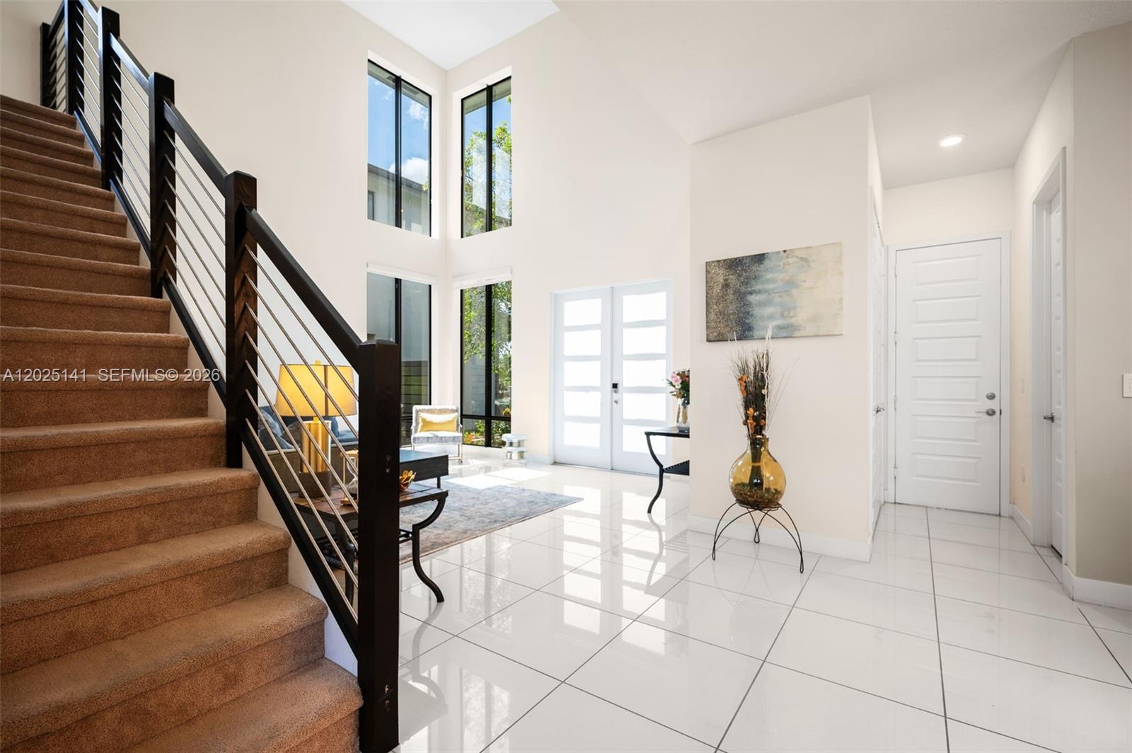 A bright foyer features white tile floors, a carpeted staircase, and tall windows — 8763 NW 157th Ter, Miami Lakes FL 33018, MIAMI LAKES, FL