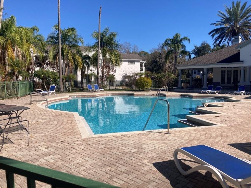 A swimming pool with a brick deck and lounge chairs sits outside a residential building — 4352 S KIRKMAN ROAD UNIT 1211, ORLANDO, FL