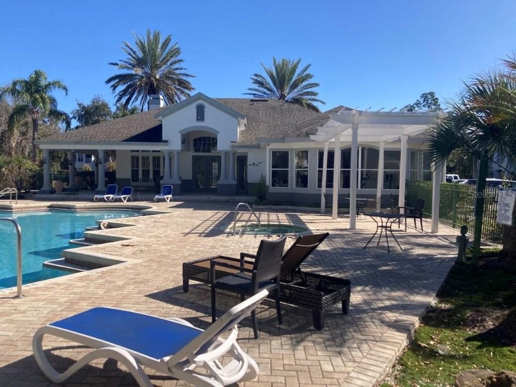 A swimming pool and hot tub sit on a paved patio beside a residential clubhouse — 4352 S KIRKMAN ROAD UNIT 1211, ORLANDO, FL