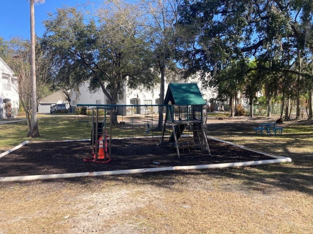 A playground with a swing set and climbing structure sits on a wood-mulched lot outdoors — 4352 S KIRKMAN ROAD UNIT 1211, ORLANDO, FL