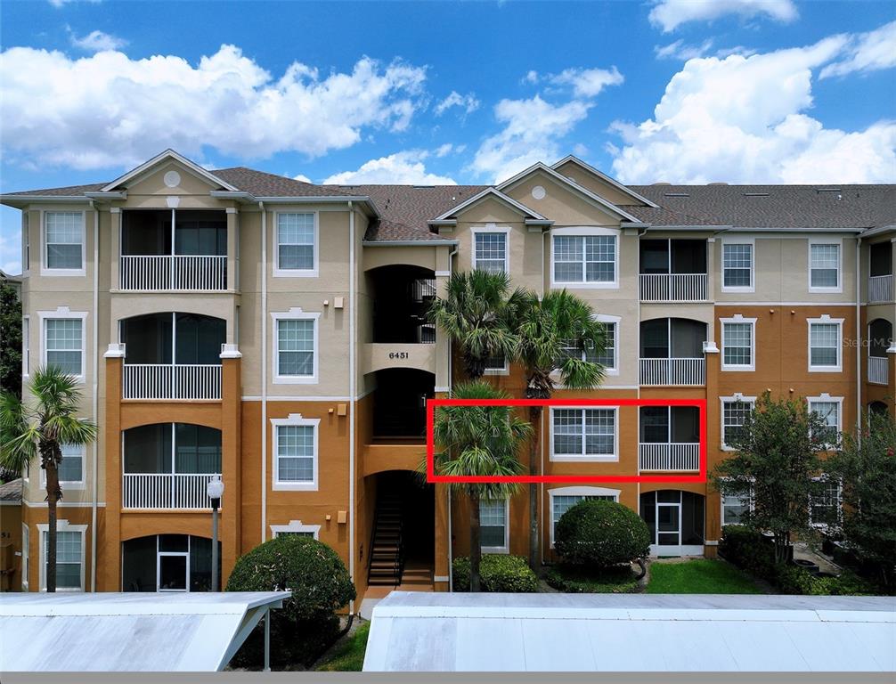 A multi-story apartment building exterior features a red-outlined balcony and windows on the second floor — 6451 OLD PARK LANE UNIT 204, ORLANDO, FL