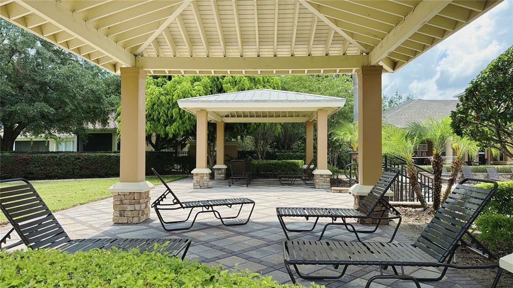 A paved patio area features several lounge chairs under a large, open-air wooden pergola — 6451 OLD PARK LANE UNIT 204, ORLANDO, FL