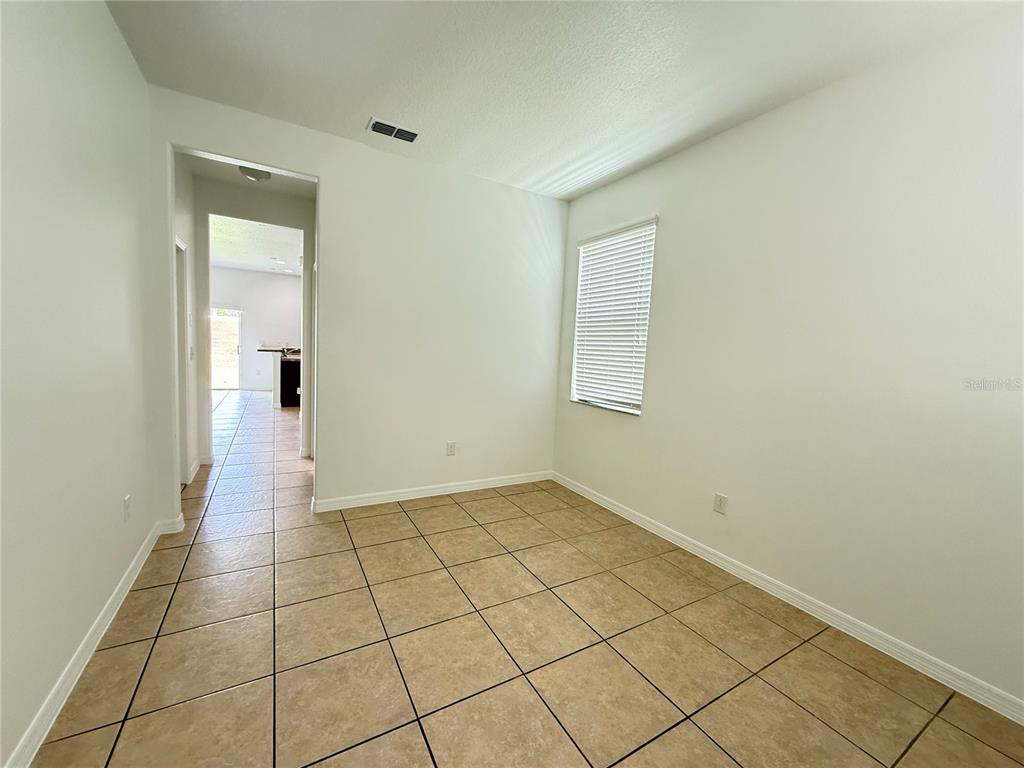 An empty room with beige tile flooring, white walls, and a window with blinds — 10713 SAVANNAH LANDING CIRCLE, ORLANDO, FL