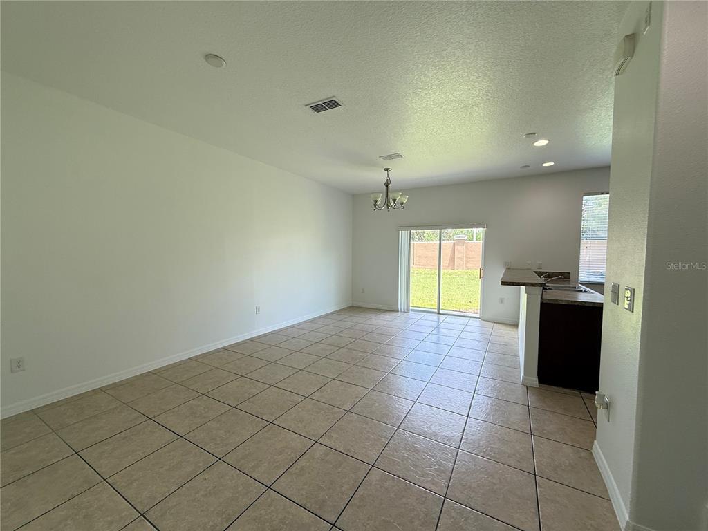 An open-concept dining area features tile flooring, a chandelier, and sliding glass doors to outside — 10713 SAVANNAH LANDING CIRCLE, ORLANDO, FL