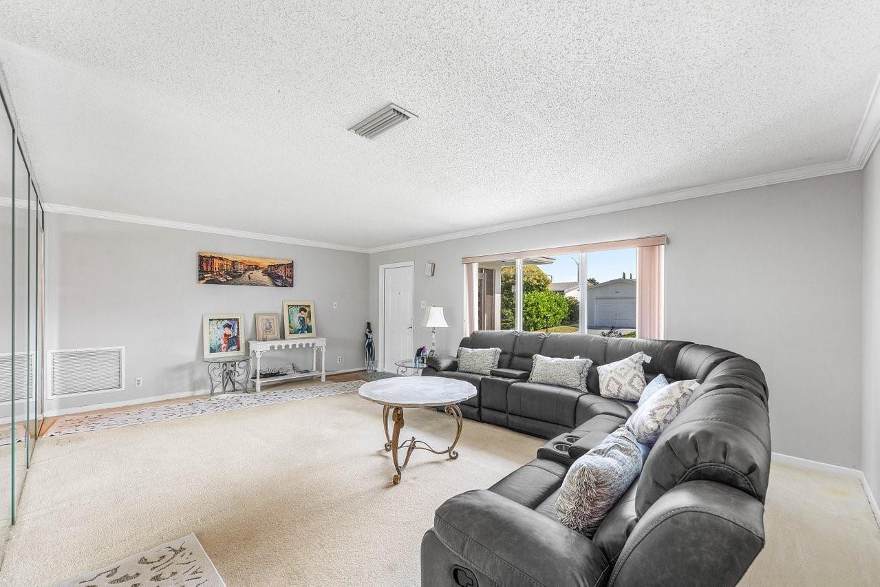 A living room features a large gray sectional sofa, a round coffee table, and carpeted floors — 745 NW 72nd Terrace, Margate FL 33063, MARGATE, FL