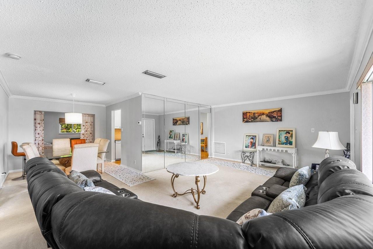 A living room features a large dark leather sectional, mirrored walls, and beige carpeting — 745 NW 72nd Terrace, Margate FL 33063, MARGATE, FL