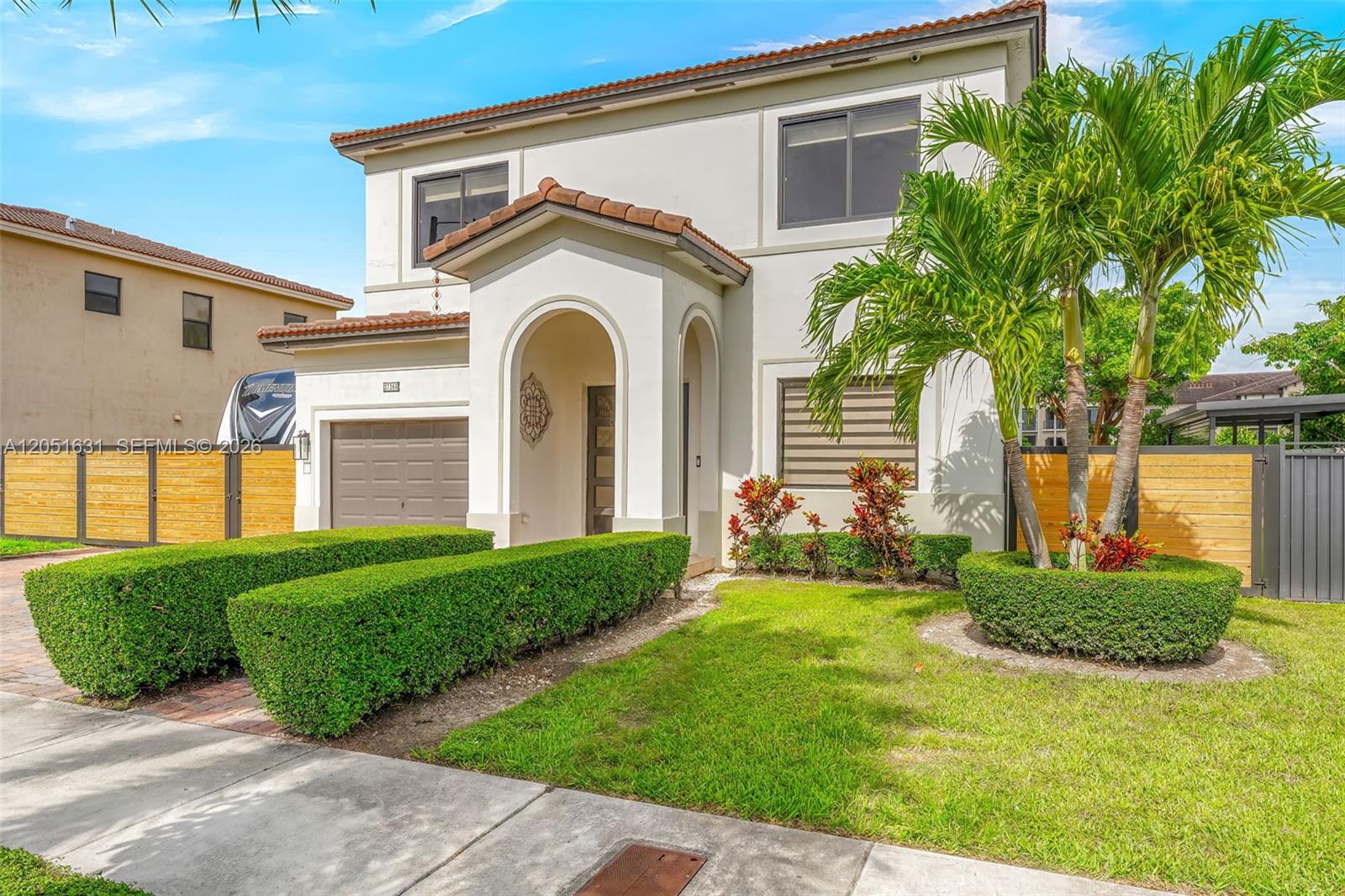A two-story house with a stucco exterior, arched entryway, garage, and manicured landscaping — 27260 SW 136th Path, Homestead FL 33032, HOMESTEAD, FL