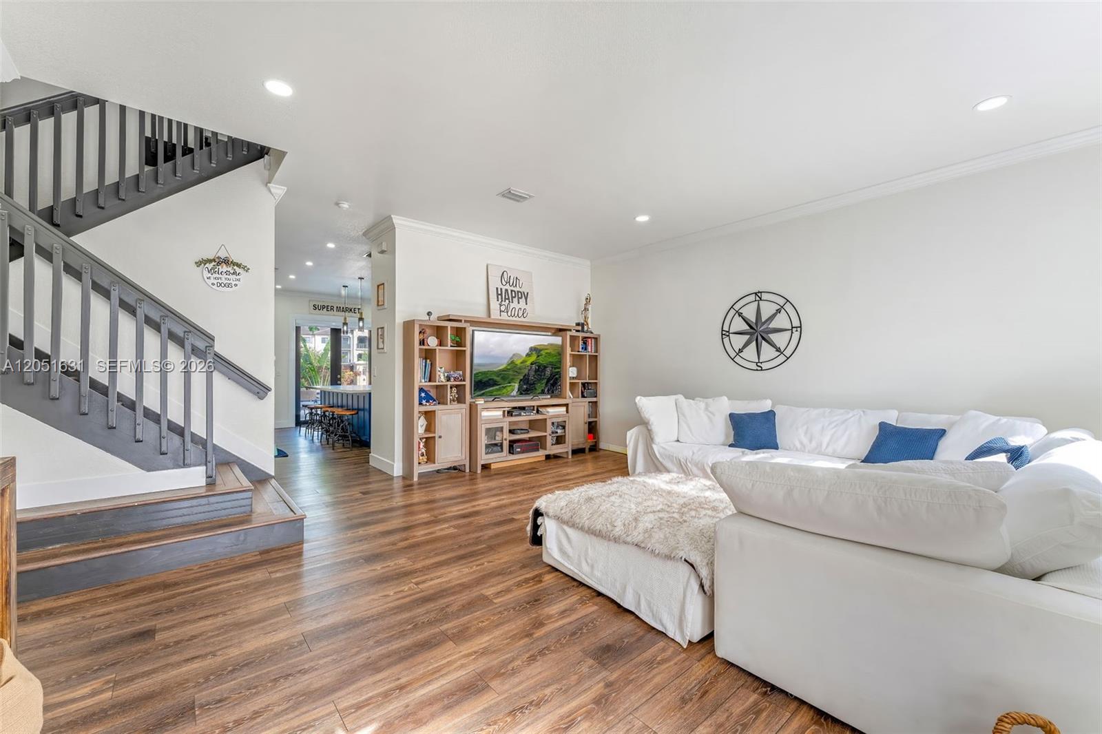 A living room features wood-look flooring, a white sectional sofa, and a staircase with dark railings — 27260 SW 136th Path, Homestead FL 33032, HOMESTEAD, FL