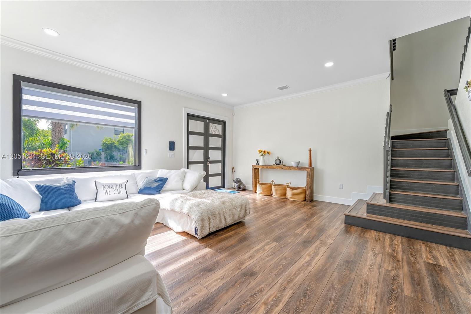 A living room features white walls, wood-look flooring, a sectional sofa, and a staircase — 27260 SW 136th Path, Homestead FL 33032, HOMESTEAD, FL