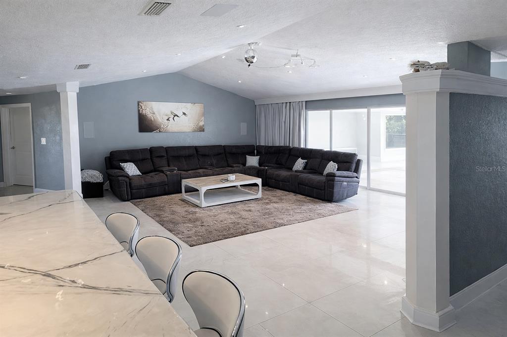 A spacious living room features a large sectional sofa, a coffee table, and tiled floors — 1840 FLAMETREE LANE, VENICE, FL