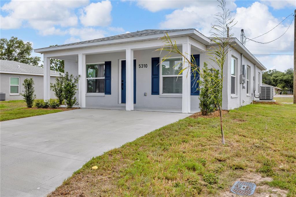 A single-story house with a gray exterior, blue shutters, a front porch, and a concrete driveway — 5310 22ND STREET COURT E, BRADENTON, FL