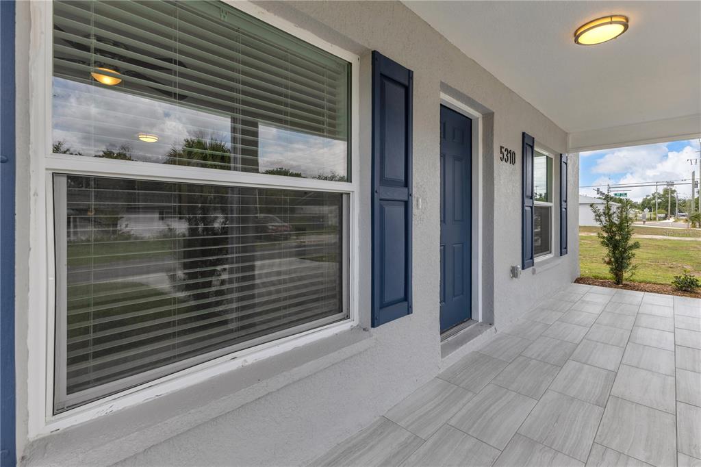 A covered front porch with gray tile flooring, a blue front door, and blue shutters — 5310 22ND STREET COURT E, BRADENTON, FL