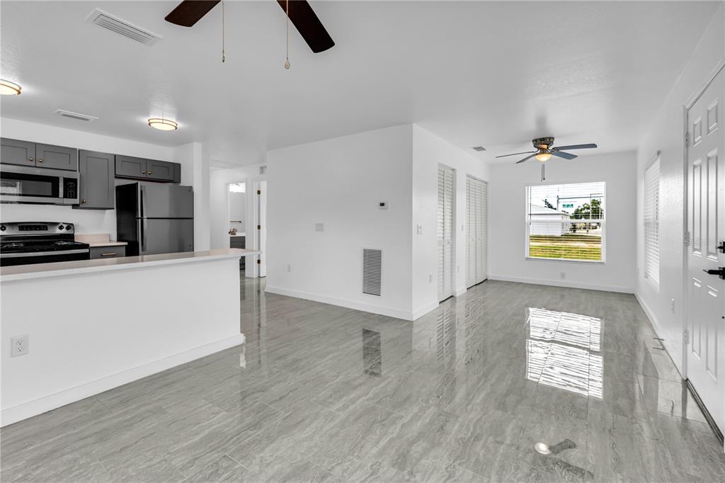 An open-concept kitchen and living area features gray cabinets, stainless appliances, and glossy tile floors — 5310 22ND STREET COURT E, BRADENTON, FL