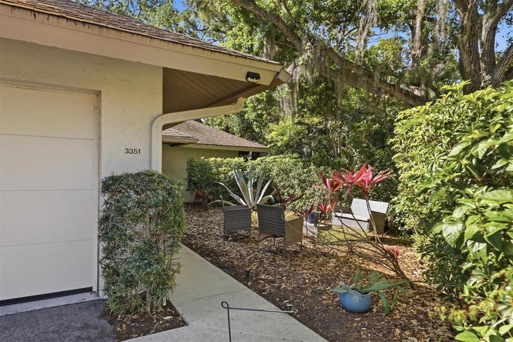 A concrete walkway leads to a small patio area with outdoor furniture beside a house — 3351 THORNWOOD ROAD UNIT 3351, SARASOTA, FL
