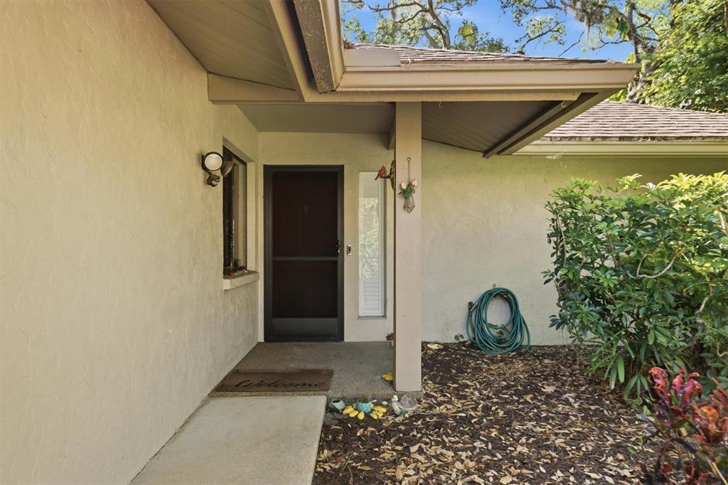 A covered concrete entryway leads to a dark front door with a screen door — 3351 THORNWOOD ROAD UNIT 3351, SARASOTA, FL