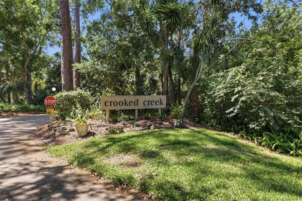 A sign reading "crooked creek" stands in a wooded area next to a stop sign — 3351 THORNWOOD ROAD UNIT 3351, SARASOTA, FL