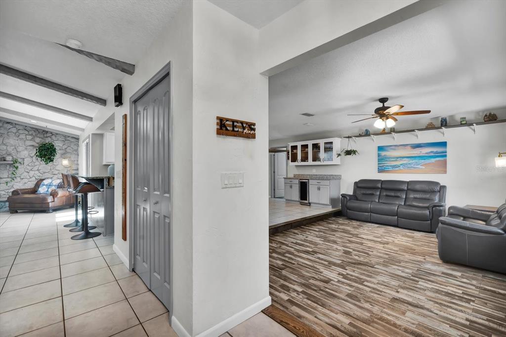 A view from a tiled hallway into a living room with wood-look flooring and furniture — 245 COUNTRY CIRCLE DRIVE E, PORT ORANGE, FL