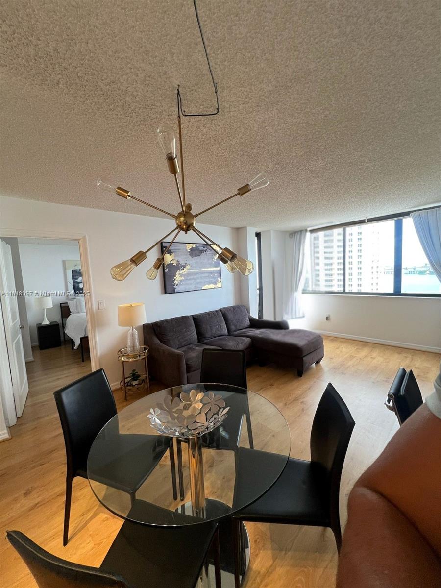 A dining area with a glass table and chandelier opens into a living room — 540 Brickell Key Dr # 1524, Miami FL 33131, MIAMI, FL
