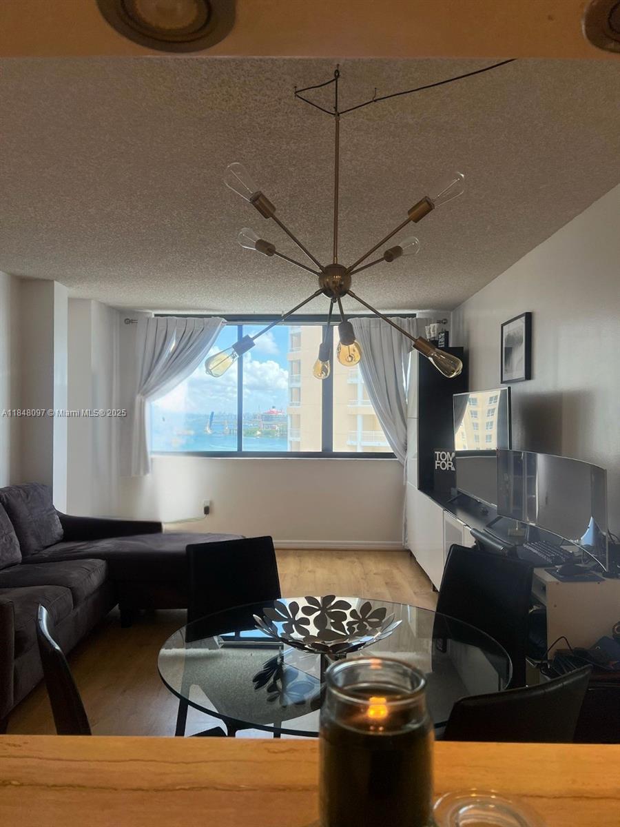 A living and dining area features a modern chandelier, glass table, and a water view — 540 Brickell Key Dr # 1524, Miami FL 33131, MIAMI, FL