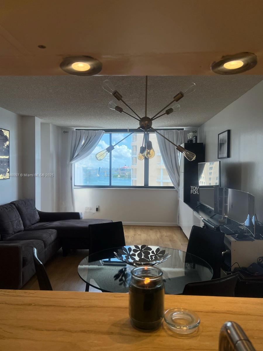 A living and dining area features a modern chandelier, glass table, and a water view — 540 Brickell Key Dr # 1524, Miami FL 33131, MIAMI, FL