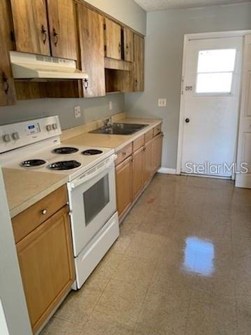 A kitchen features wood cabinets, a white electric stove, and a door leading outside — 2830 SKYVIEW DRIVE, LAKELAND, FL
