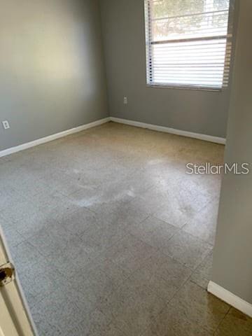 An empty bedroom with gray walls, a window with blinds, and light-colored tile flooring — 2830 SKYVIEW DRIVE, LAKELAND, FL