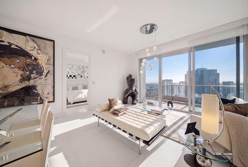 A modern living room features a white daybed, glass coffee table, and floor-to-ceiling windows — 200 Biscayne Boulevard Way # 5110, Miami FL 33131, MIAMI, FL