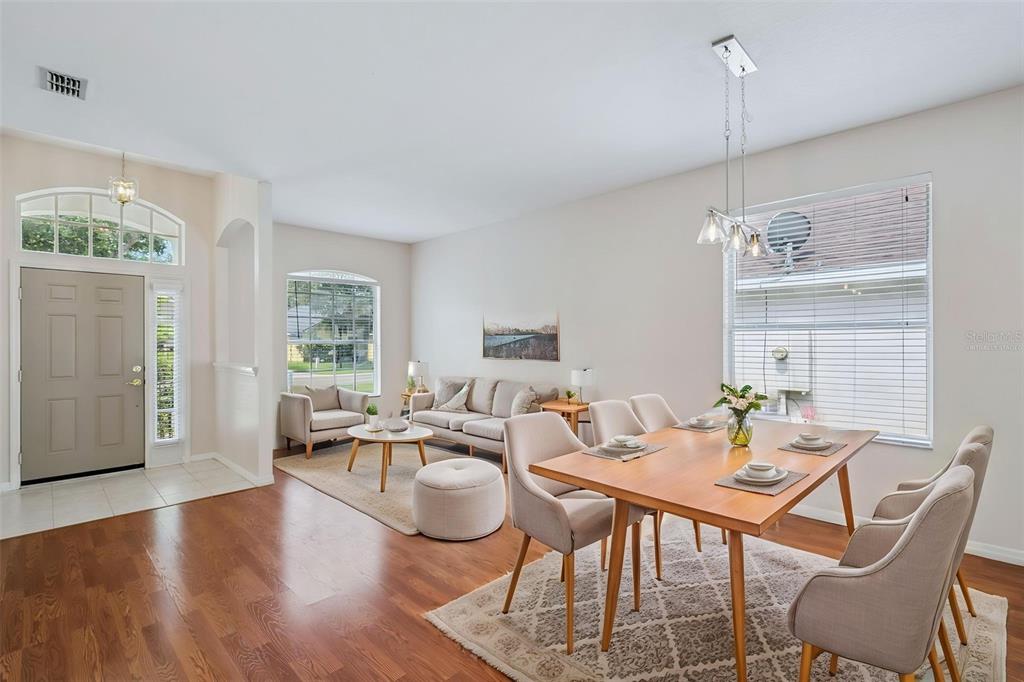 An open-concept living and dining area features hardwood floors, neutral walls, and large windows — 223 EASTON CIRCLE, OVIEDO, FL