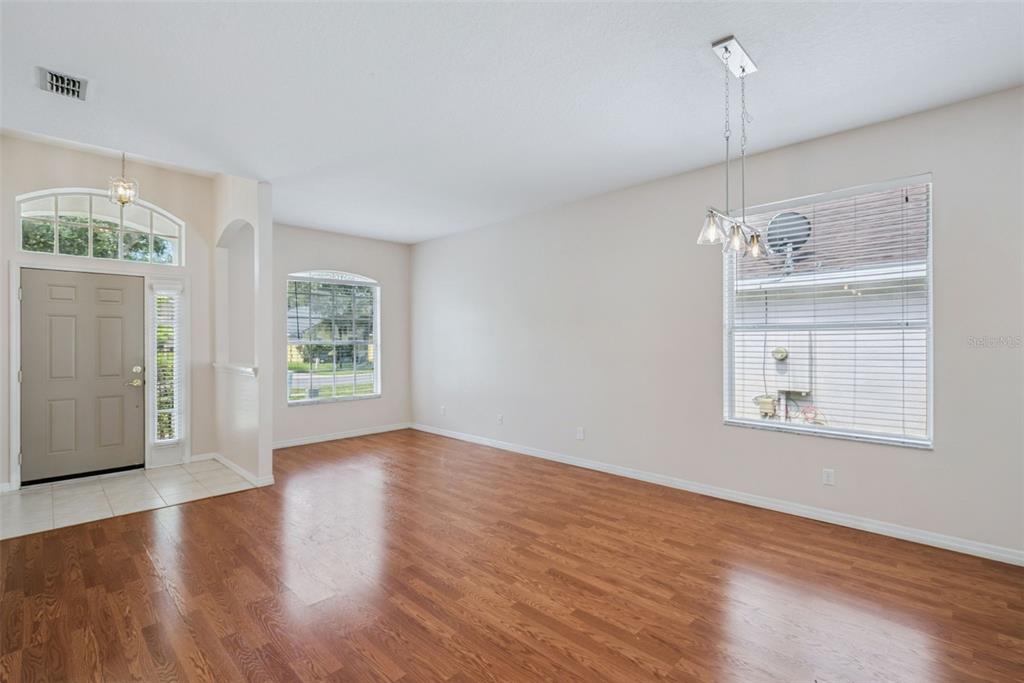An empty room with wood-look flooring, a light fixture, and windows with white blinds — 223 EASTON CIRCLE, OVIEDO, FL