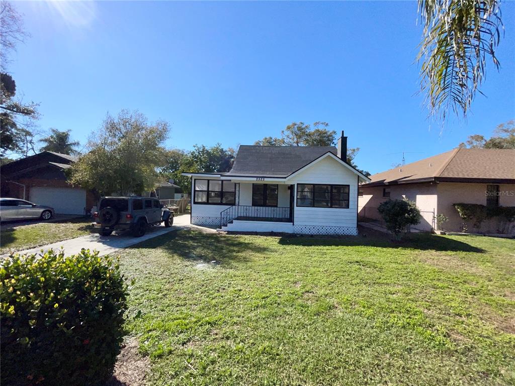 A white single-story house with a black roof and a driveway sits on a lawn — 2525 37TH STREET S, ST PETERSBURG, FL